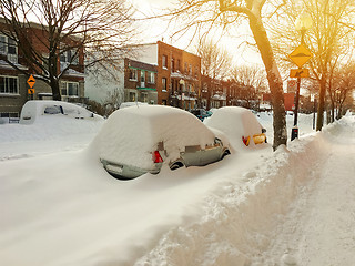 Image showing Cars covered with snow on winter street in sunset