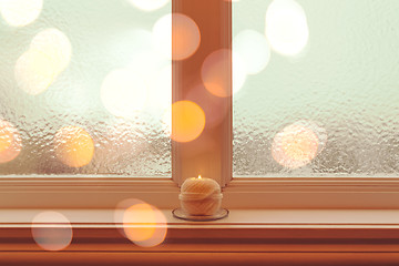 Image showing Frosted winter window and candle in golden light