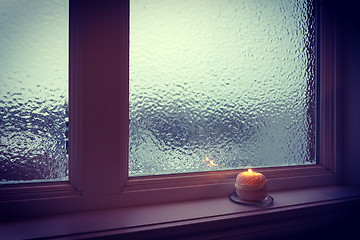 Image showing Candle burning near a frosted window in twilight