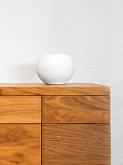 Image showing Simple ceramic vase decorating a chest of drawers