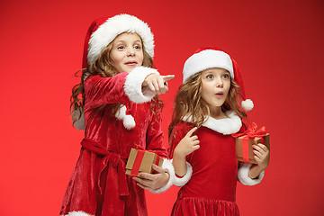 Image showing Two happy girls in santa claus hats with gift boxes