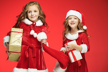 Image showing Two happy girls in santa claus hats with gift boxes