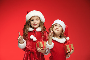 Image showing Two happy girls in santa claus hats with gift boxes