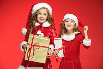 Image showing Two happy girls in santa claus hats with gift boxes