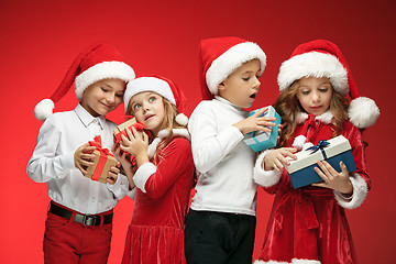 Image showing Two happy girls and boys in santa claus hats with gift boxes