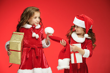 Image showing Two happy girls in santa claus hats with gift boxes at studio