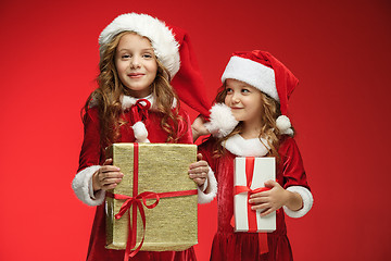 Image showing Two happy girls in santa claus hats with gift boxes at studio