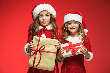 Image showing Two happy girls in santa claus hats with gift boxes at studio