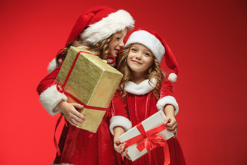 Image showing Two happy girls in santa claus hats with gift boxes at studio