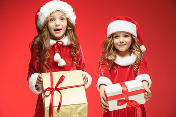 Image showing Two happy girls in santa claus hats with gift boxes at studio