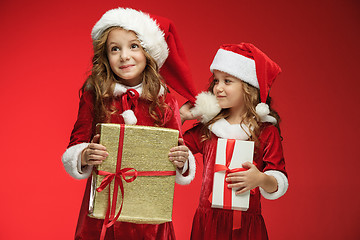 Image showing Two happy girls in santa claus hats with gift boxes at studio