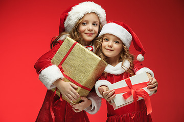 Image showing Two happy girls in santa claus hats with gift boxes at studio