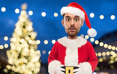 Image showing man in santa claus costume over christmas lights