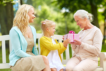 Image showing happy family giving present to grandmother at park