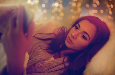 Image showing young woman with smartphone in bed at home bedroom