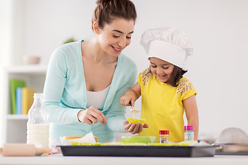Image showing happy mother and daughter baking cupcakes at home