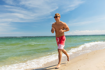 Image showing happy man running along summer beach