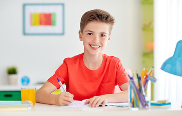 Image showing happy student boy writing to notebook at home