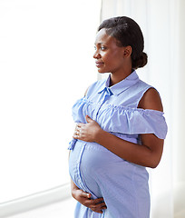 Image showing pregnant woman looking through window at home