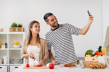 Image showing couple cooking food and taking selfie at kitchen