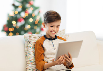Image showing smiling boy with tablet pc at home at christmas
