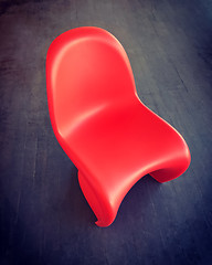 Image showing Red plastic chair on dark wooden floor