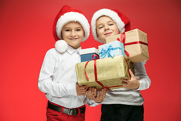 Image showing Two happy boys in santa claus hats with gift boxes at studio