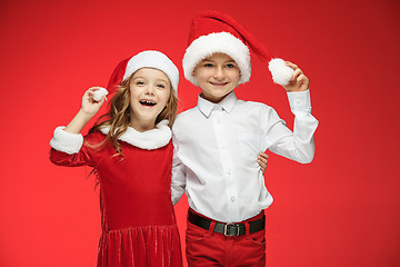 Image showing Two happy boy and girl in santa claus hats with gift boxes at studio