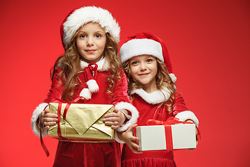 Image showing Two happy girls in santa claus hats with gift boxes at studio