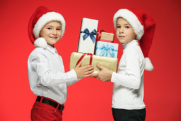 Image showing Two happy boys in santa claus hats with gift boxes at studio