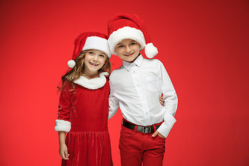 Image showing Two happy boy and girl in santa claus hats with gift boxes at studio