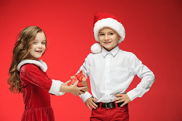 Image showing Two happy boy and girl in santa claus hats with gift boxes at studio