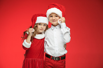 Image showing Two happy boy and girl in santa claus hats with gift boxes at studio