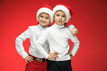 Image showing Two happy boys in santa claus hats with gift boxes at studio