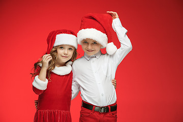 Image showing Two happy boy and girl in santa claus hats with gift boxes at studio