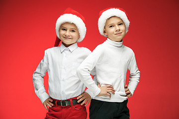 Image showing Two happy boys in santa claus hats with gift boxes at studio