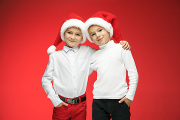 Image showing Two happy boys in santa claus hats with gift boxes at studio