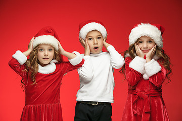 Image showing The happy boy and girls in santa claus hats with gift boxes at studio