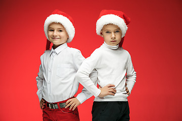 Image showing Two happy boys in santa claus hats with gift boxes at studio