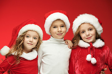 Image showing The happy boy and girls in santa claus hats with gift boxes at studio