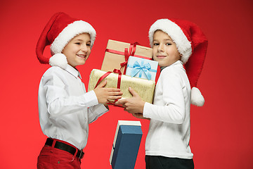 Image showing Two happy boys in santa claus hats with gift boxes at studio