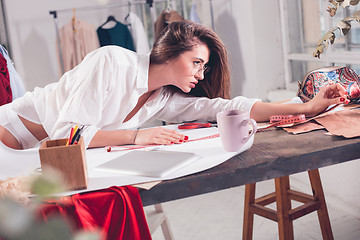 Image showing Fashion designers working in studio sitting on the desk