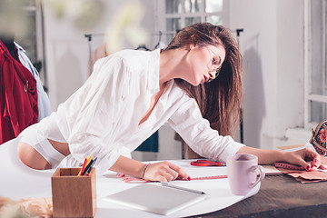 Image showing Fashion designers working in studio sitting on the desk