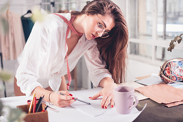 Image showing Fashion designers working in studio sitting on the desk