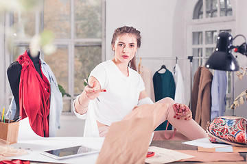 Image showing Fashion designers working in studio sitting on the desk