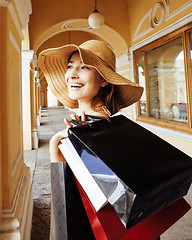 Image showing young pretty smiling woman in hat with bags on shopping at store