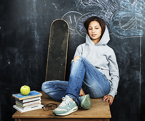 Image showing young cute teenage girl in classroom at blackboard seating on ta