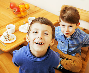 Image showing little cute boys eating dessert on wooden kitchen. home interior