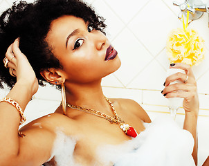 Image showing young afro-american teen girl laying in bath with foam, wearing 