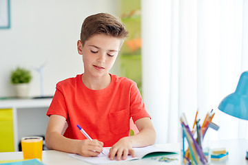 Image showing happy student boy writing to notebook at home